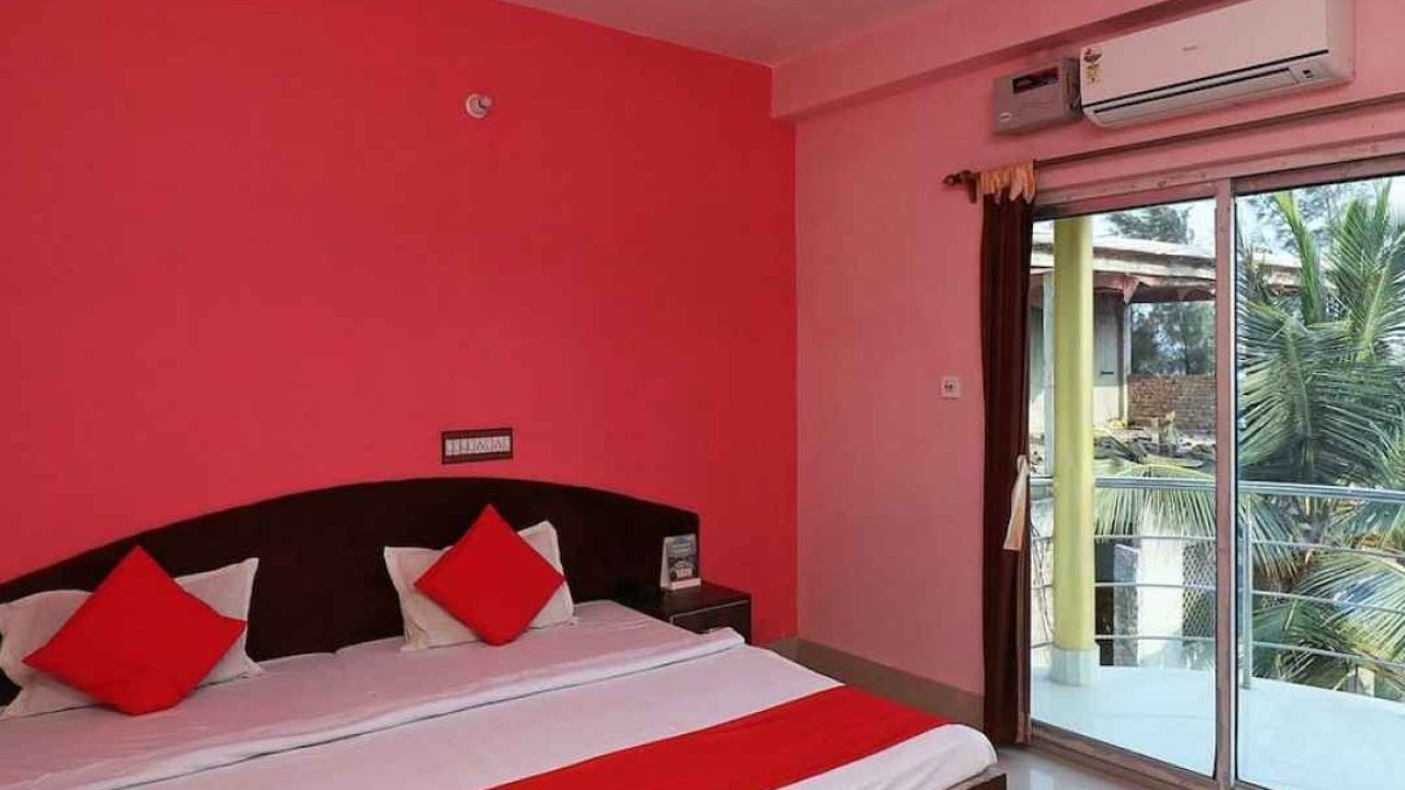 S2 Hotel room with attached balcony, AC, clean bed, and pink-colored walls in Sundarban